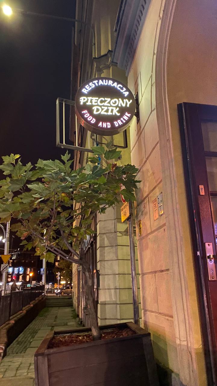 Wejście do restauracji Pieczony Dzik we Wrocławiu z podświetlanym szyldem